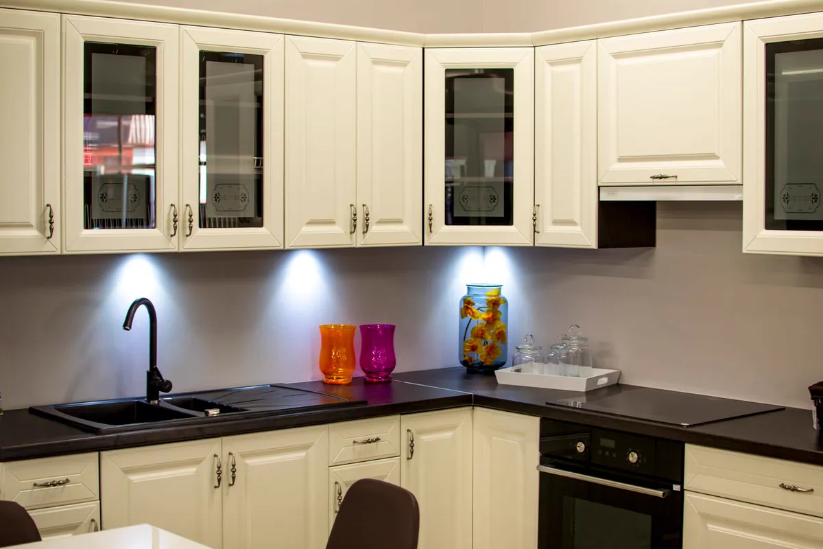 White raised-panel kitchen cabinets with glass-front uppers and dark countertops