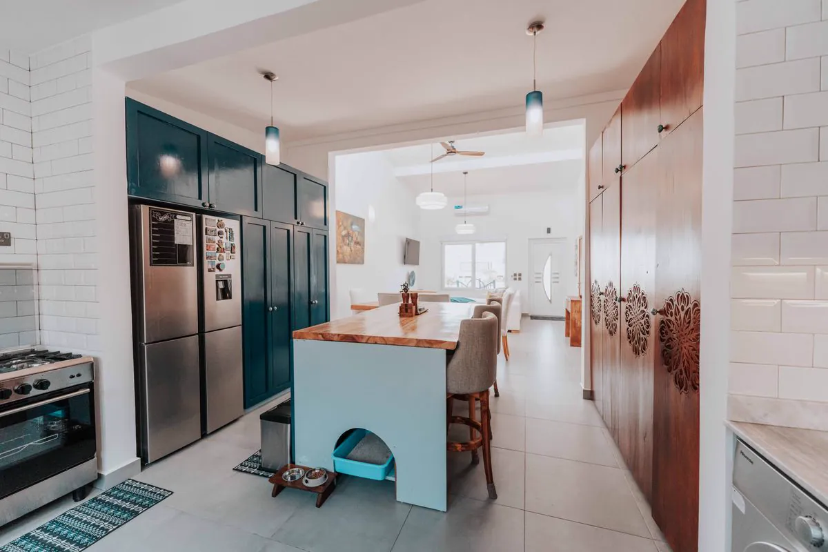 Kitchen with teal shaker cabinets, a wood-top island and carved wood pantry doors