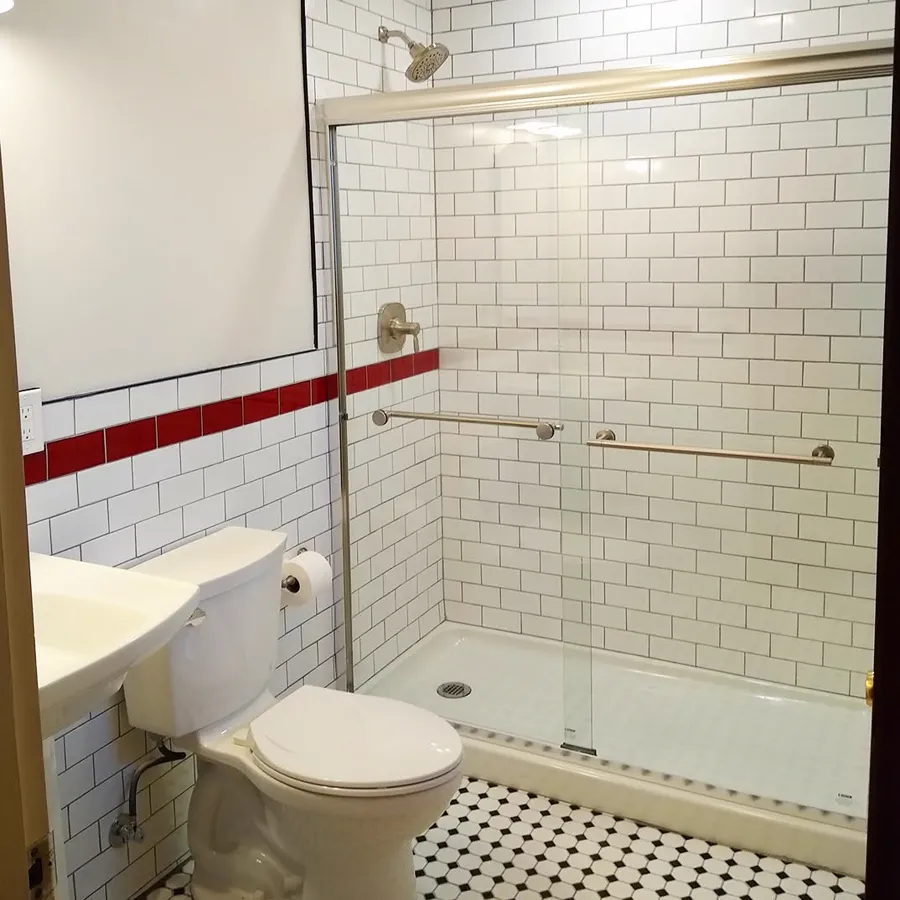 Bathroom with white subway tile, a red tile stripe and a sliding glass shower door