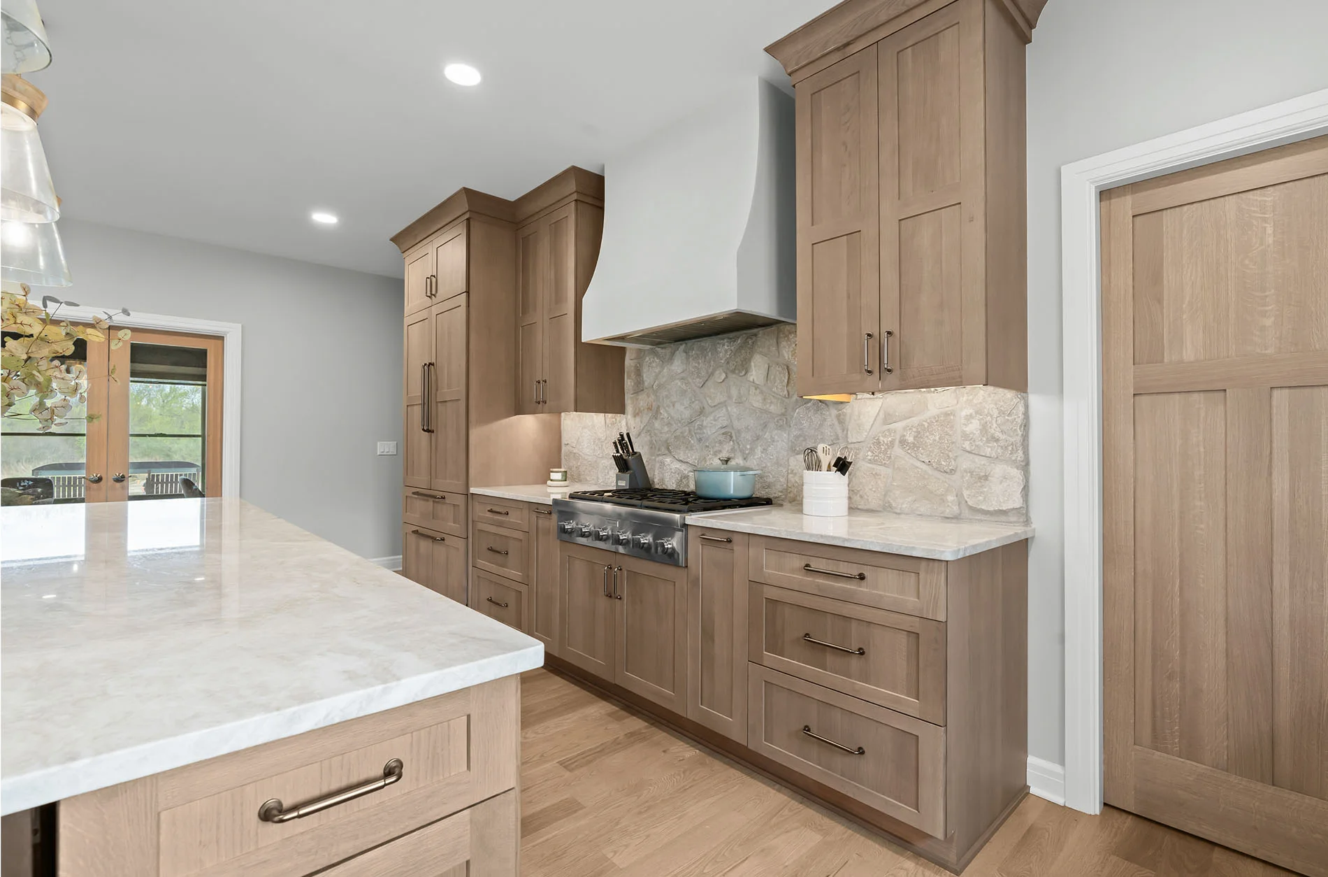 Plaster range hood and natural stone full-height backsplash