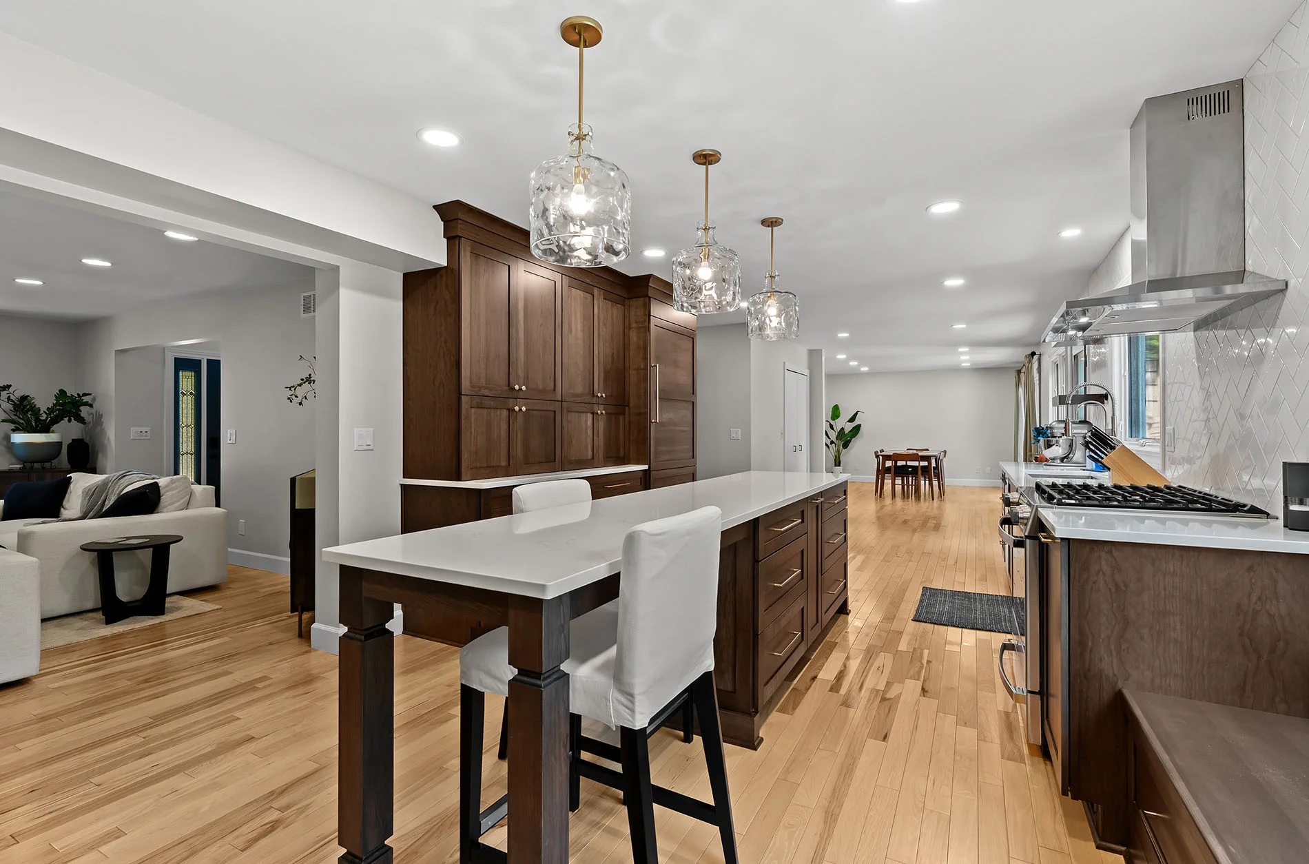 Cherry cabinetry with white quartz counters and gold pendants